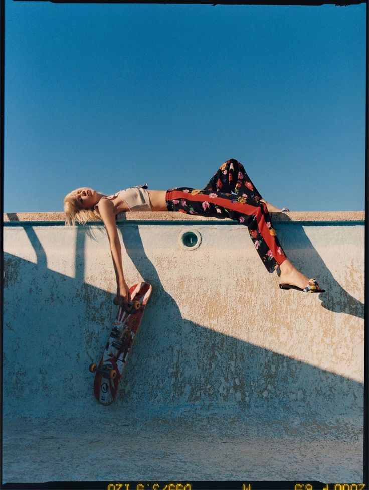 a woman laying on top of a skateboard next to a wall