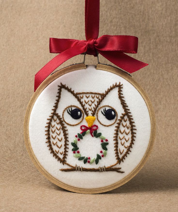 an embroidered owl ornament with a red ribbon hanging from it's side