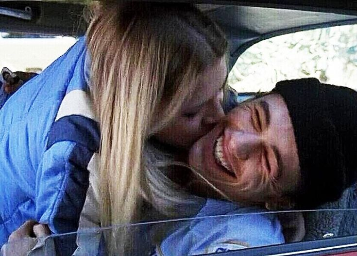 a man and woman sitting in the back seat of a car, one is smiling