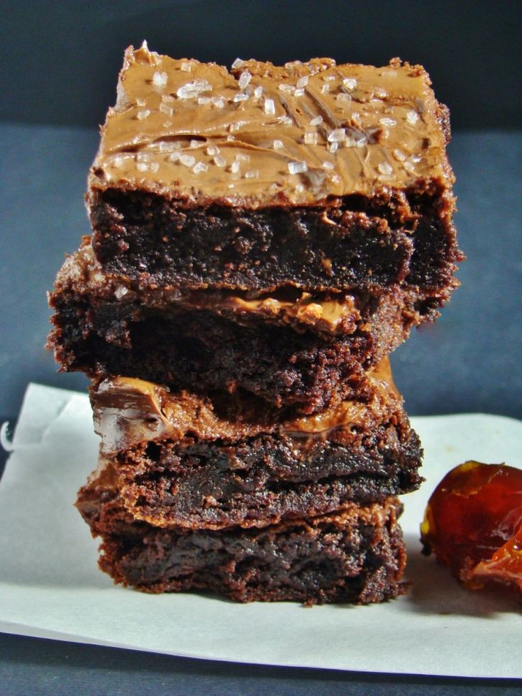 a stack of brownies sitting on top of a white plate next to a piece of fruit