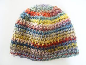 a multicolored knitted hat hanging on a white wall next to a pair of scissors