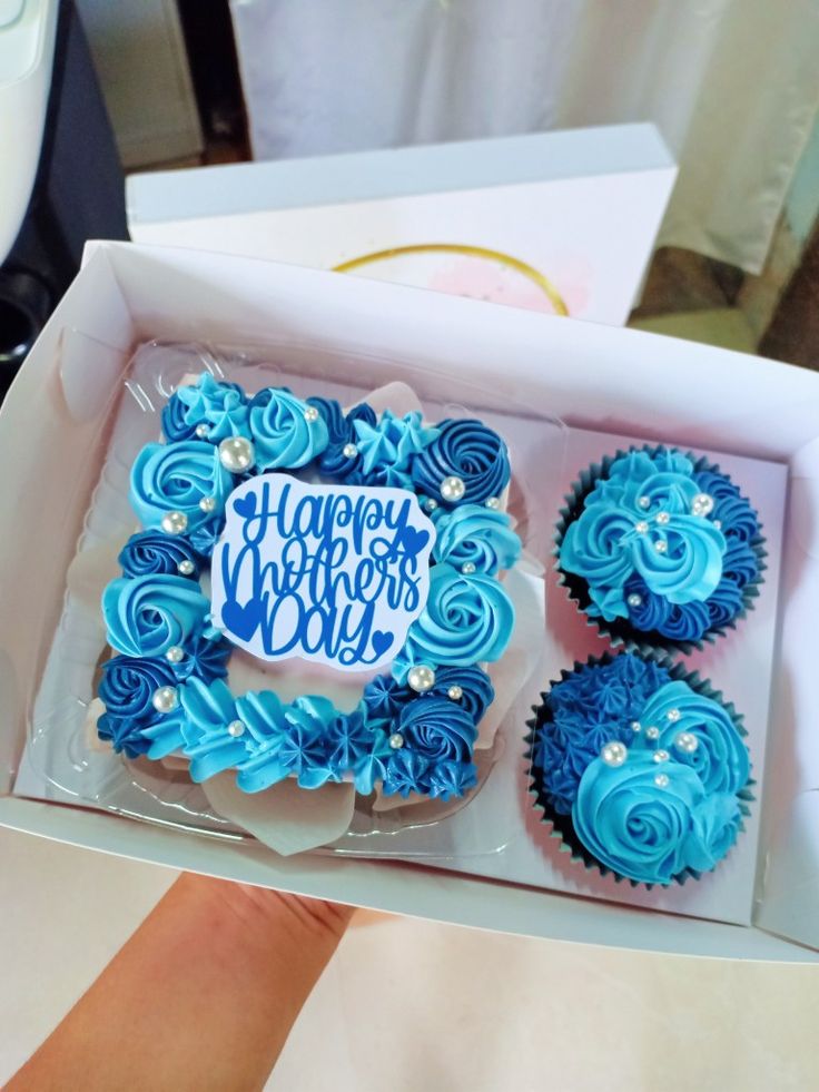 blue cupcakes in a box with happy birthday written on them, sitting next to each other