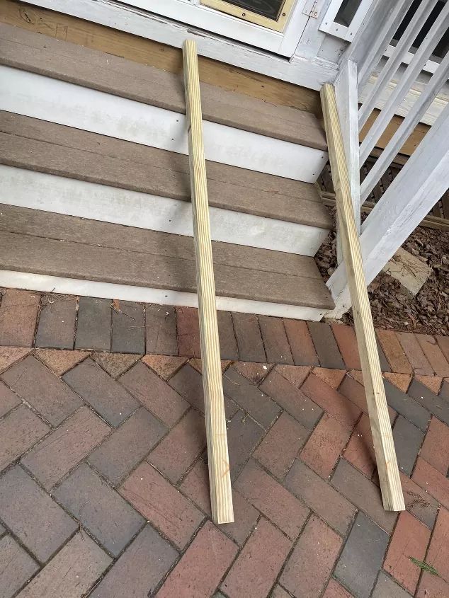 two wooden poles sticking out of the side of a porch next to a brick walkway