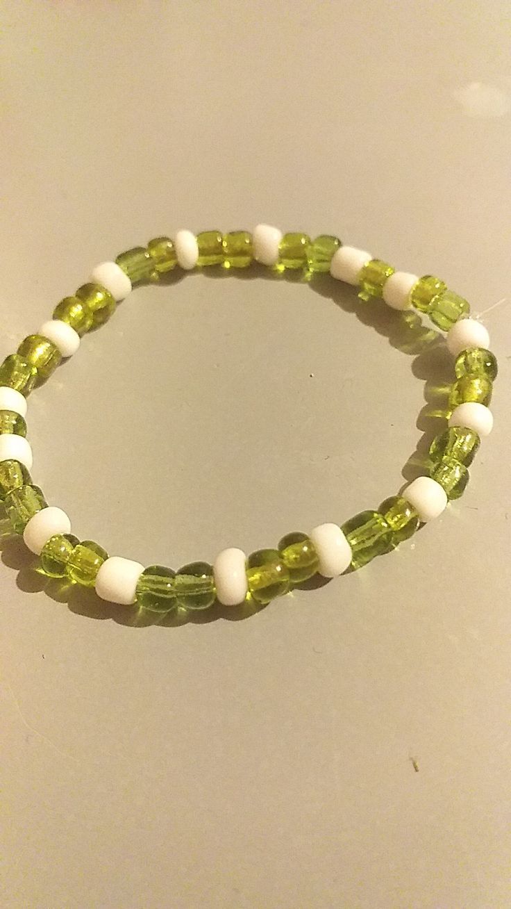 a green and white beaded bracelet sitting on top of a table