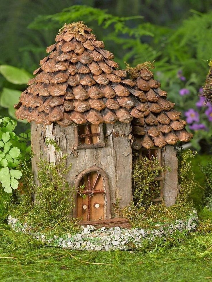 a small house made out of wood and clay with moss growing on the roof, surrounded by greenery