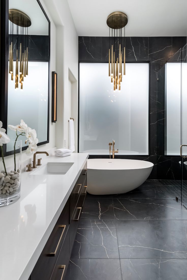 a bathroom with black and white marble flooring, gold fixtures and chandeliers