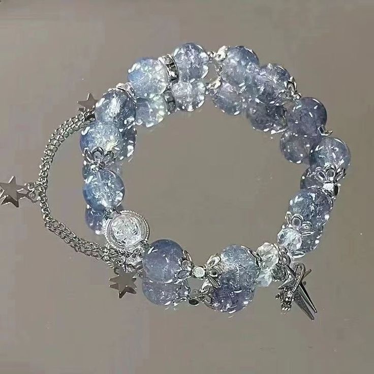 This exquisite bracelet is a masterpiece of celestial charm, each bead a miniature galaxy, swirling with a mesmerizing mix of dark blues and cosmic whites. Crafted with crystal-clear attention to detail, the beads catch the light, sparkling like distant stars against the night sky. A delicate silver chain tethers charming pendants, symbols of dreams and the boundless realm of the imagination. What truly sets this piece apart is the story it tells--the tale of stardust and enchantment, where every gesture of your hand becomes an ethereal dance of light and shadow. It's not just an accessory; it's a gateway to a world where magic is real and every moment is sprinkled with wonder. Ideal for the dreamer's soul, this bracelet doesn't simply adorn your wrist--it enchants it, transforming the ord Star Beads, Friend Jewelry, Best Friend Jewelry, Friendship Jewelry, Tassel Bracelet, Versatile Jewelry, Crystal Beads Bracelet, Bracelet Boho, Star Bracelet