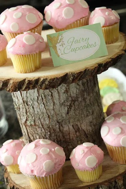 cupcakes are arranged on top of a tree stump