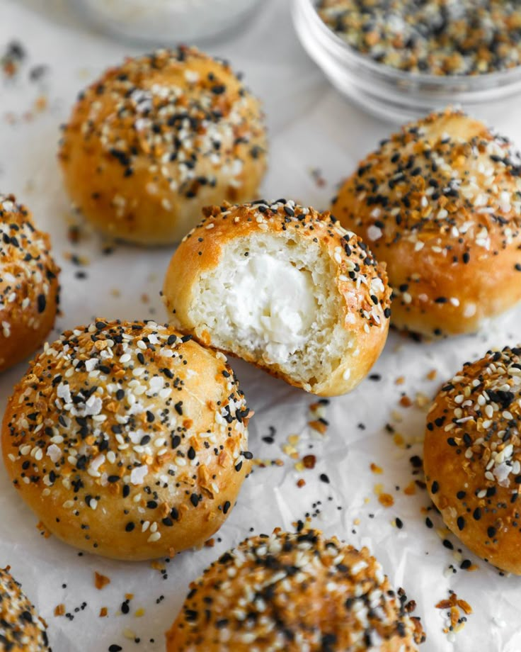 sesame seed bagels with cream cheese and sprinkles on white parchment paper