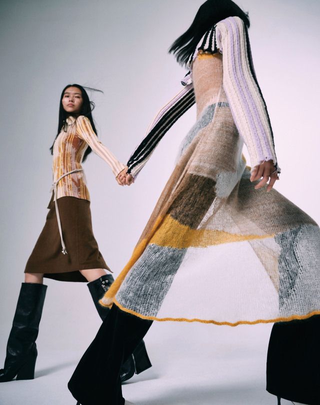 two women in long skirts and boots are holding hands