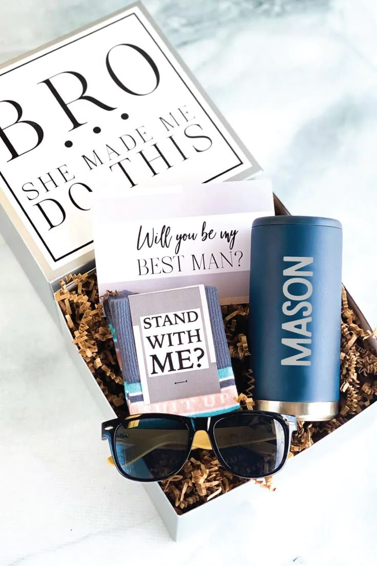 an open box with sunglasses, coffee cup and brochure in it on a marble surface