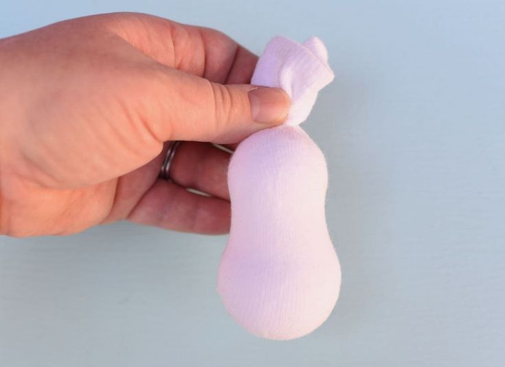 a hand holding a small pink object in it's left hand on a white surface