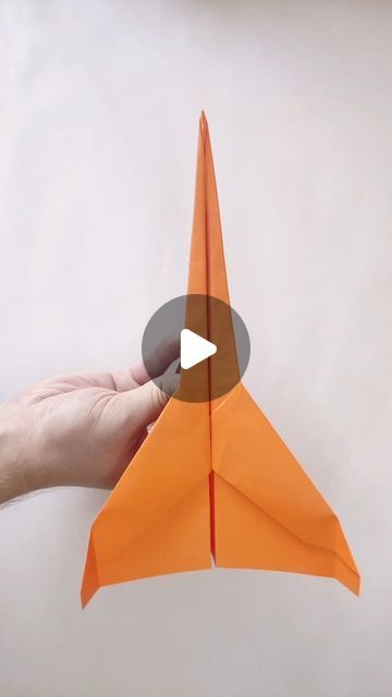 someone holding an orange origami airplane in their hand