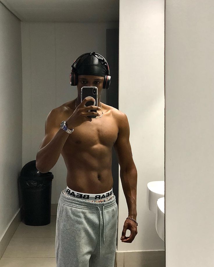 a shirtless man taking a selfie in the mirror with his cell phone and helmet on