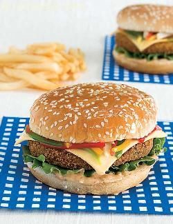 two hamburgers with cheese, lettuce and tomato on blue placemats