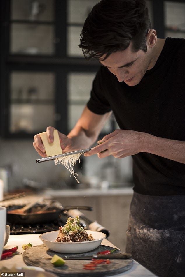 a man in black shirt preparing food on top of a white plate with utensils