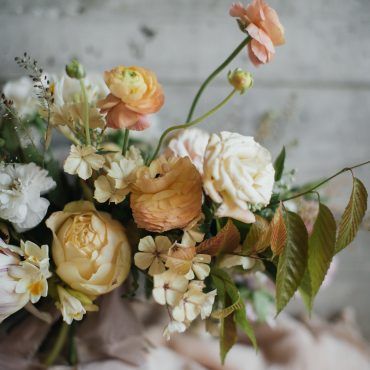 a bunch of flowers that are sitting in a vase on a cloth covered tablecloth