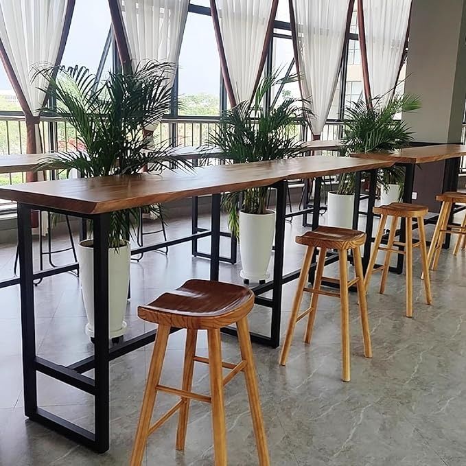 the tables and stools are lined up in front of large windows with plants on them