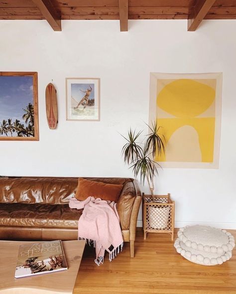 a brown leather couch sitting in a living room next to a wooden table and potted plant