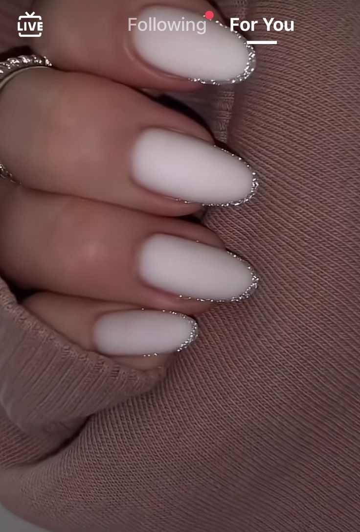 a woman's hand with white manies and glitters on her nails, wearing a beige sweater