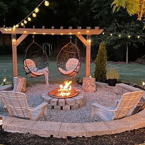 a fire pit with chairs around it and string lights strung across the top, above which is a hammock