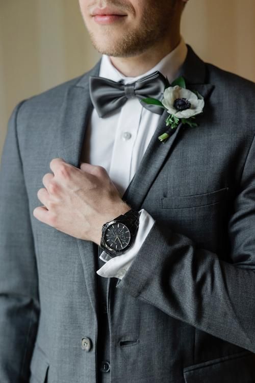 a man in a suit and bow tie is looking at the camera while wearing a watch