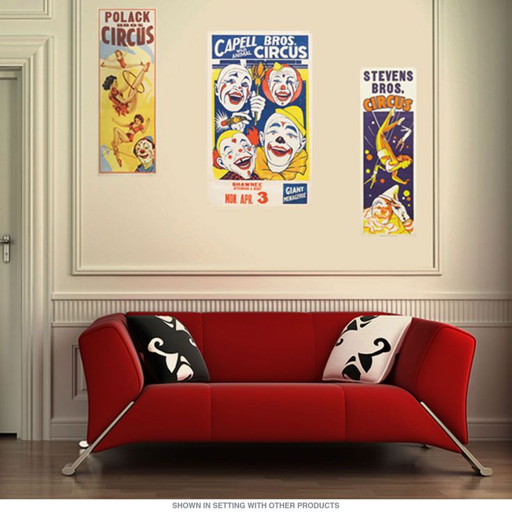 a red couch sitting next to a white wall with posters on it's walls