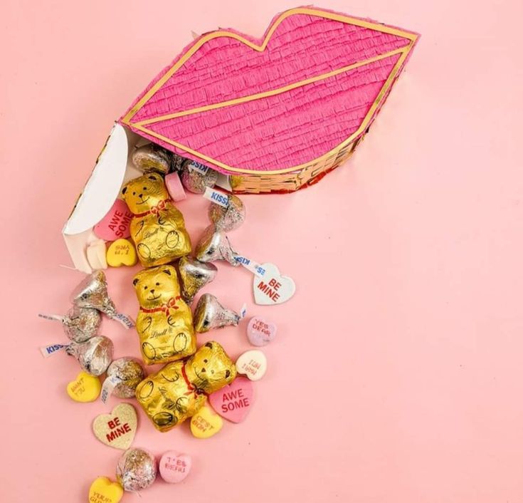 a basket filled with lots of candy on top of a pink surface