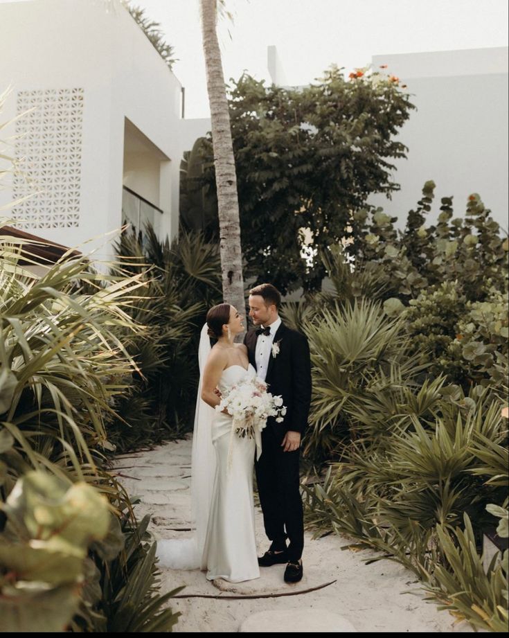 a bride and groom standing in front of palm trees