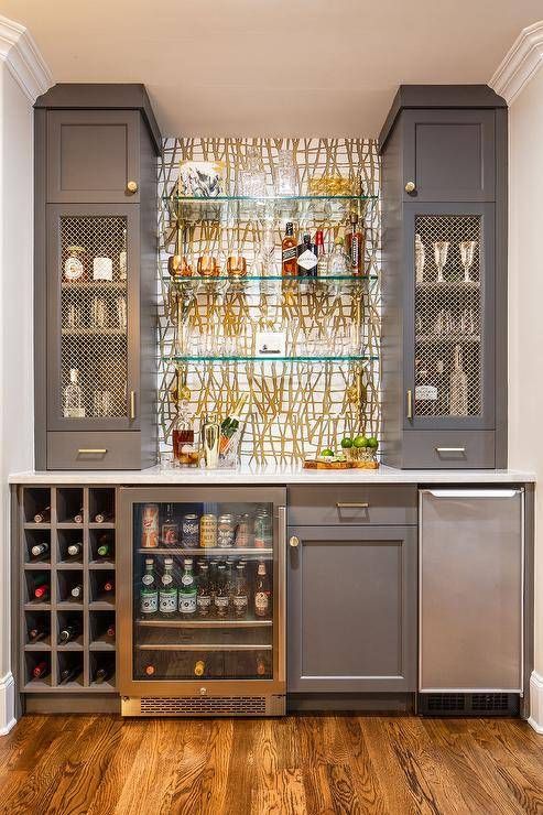 a kitchen with gray cabinets and shelves filled with bottles, wine glasses and other items