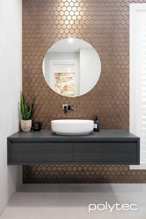 a bathroom with a sink, mirror and plant on the counter in front of it