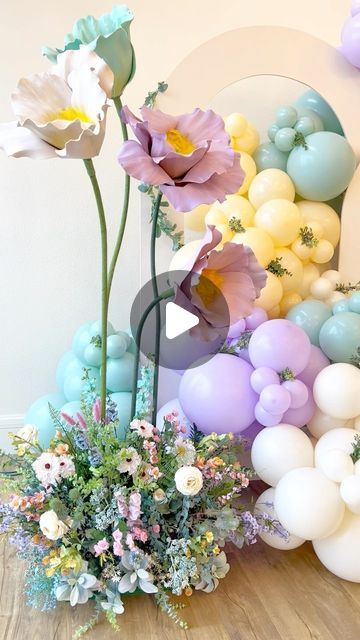 there are balloons and flowers on the floor in front of a wall that is decorated with pastel colors