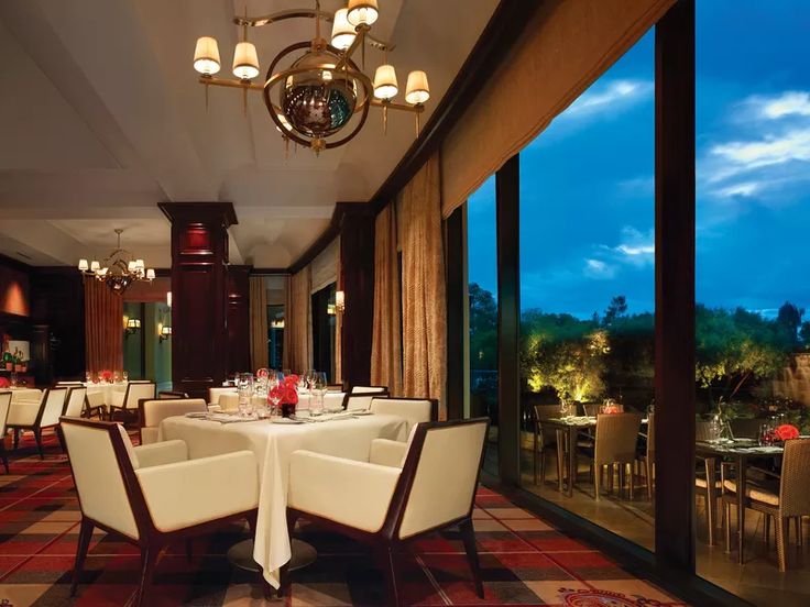 a dining room with tables, chairs and windows looking out onto the outdoors at night