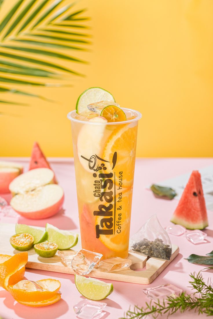 a glass filled with orange juice next to slices of watermelon