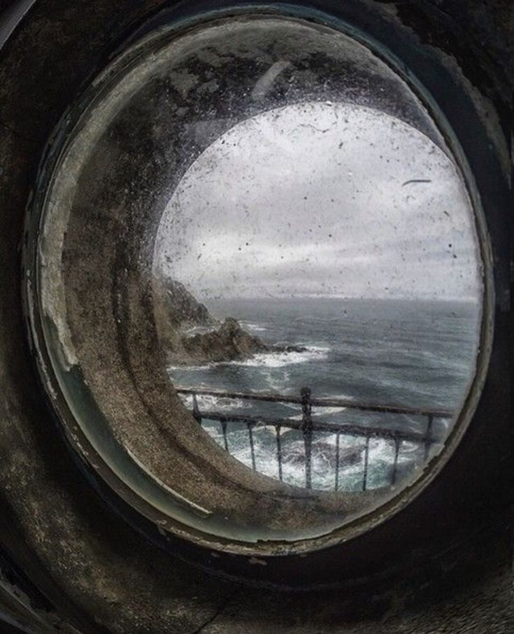 a round window in the side of a ship looking out at the ocean and waves