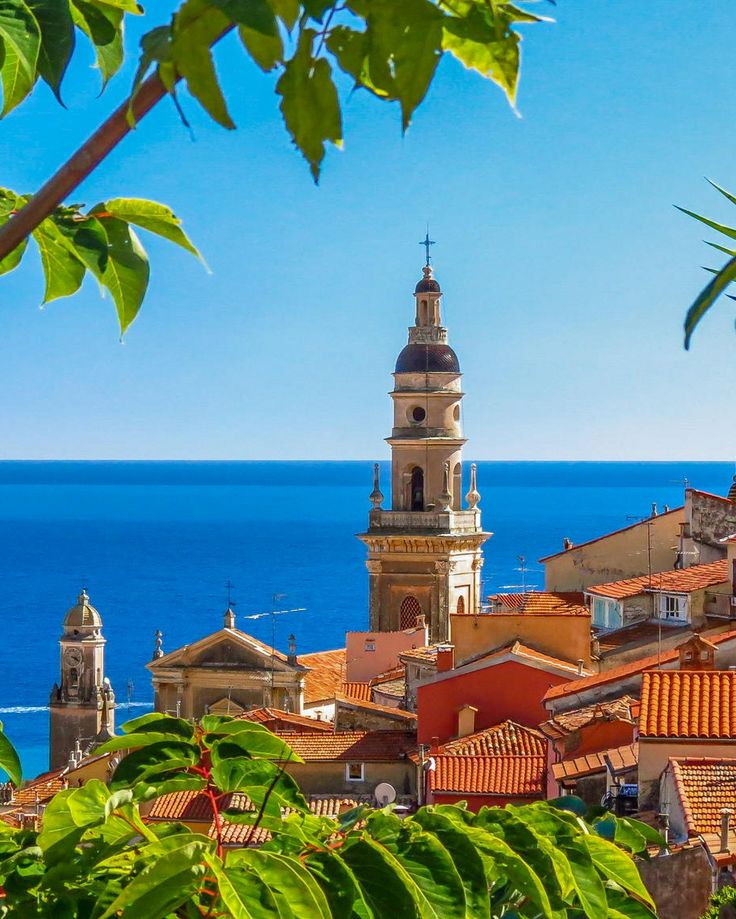 an old town by the ocean with a steeple in the background and blue sky