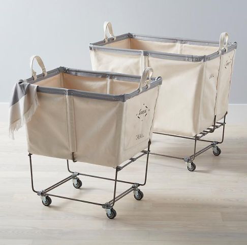 three canvas laundry baskets on wheels with handles and liners, one in beige and the other in grey