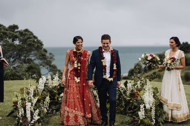 the bride and groom are walking down the aisle to their wedding ceremony in front of the ocean