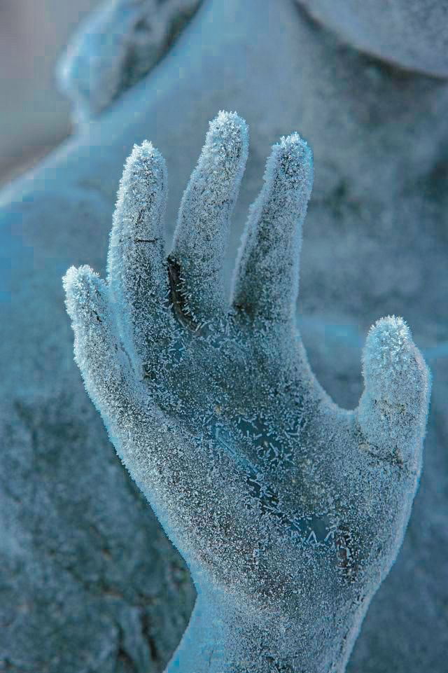 a person with their hand in the air and frost on his hands, against a blue background