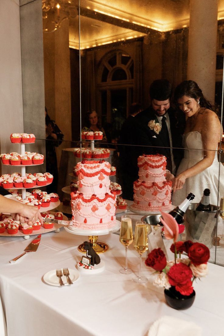 a bride and groom are cutting their wedding cake at the reception table with red roses