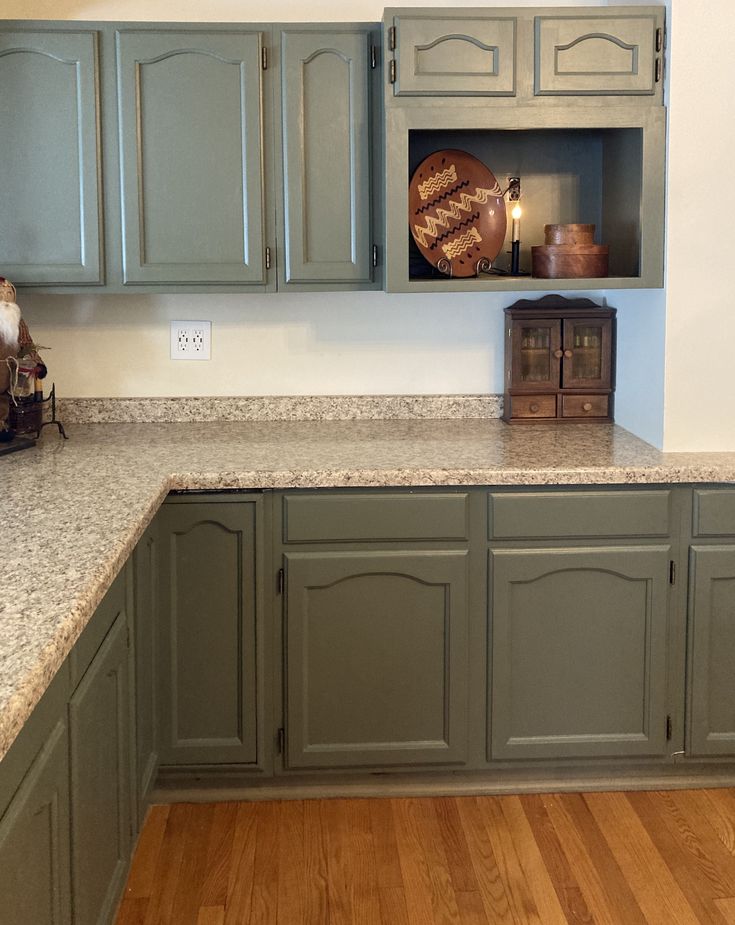 an empty kitchen with green cabinets and wood flooring on the counter top, in front of a lit candle