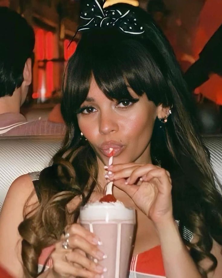 a woman holding a drink with a straw in her mouth