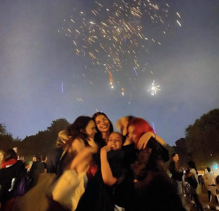 a group of people standing next to each other with fireworks in the sky