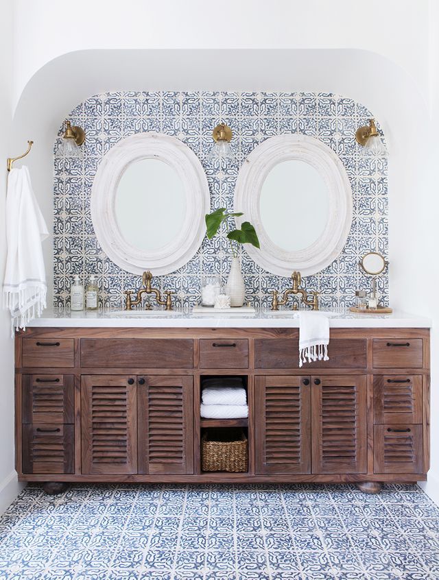 a bathroom with two sinks and mirrors on the wall next to each other in front of a blue patterned wall