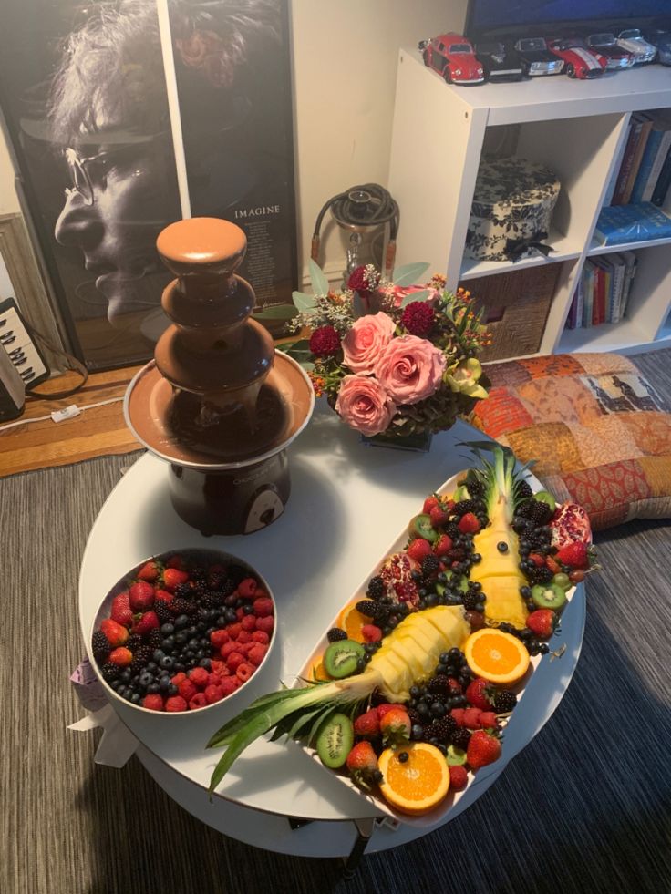 a table topped with two trays filled with fruit and chocolate fountain on top of it