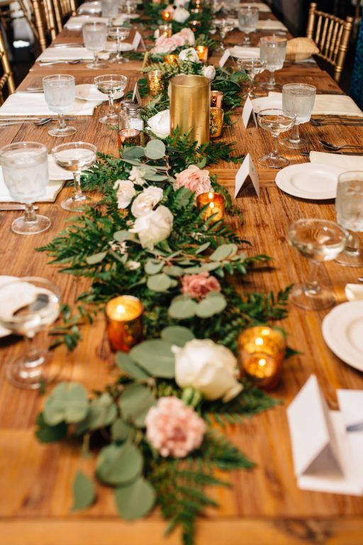 a long table with flowers and greenery is set up for a formal dinner party