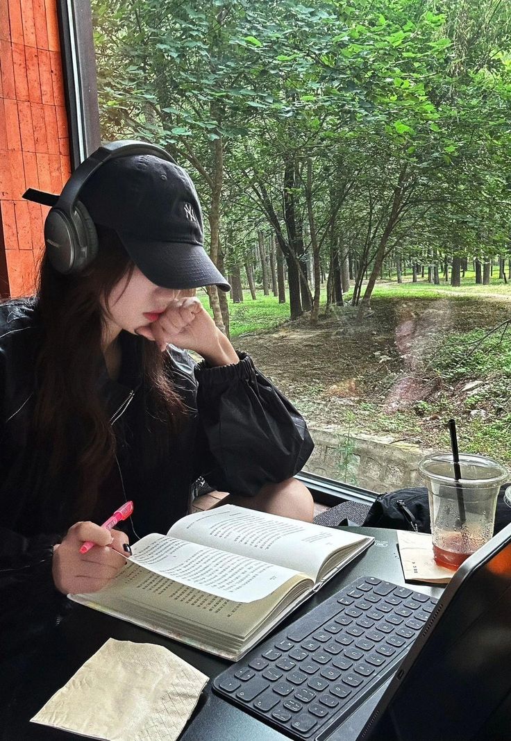 a woman sitting at a table with an open book and headphones on