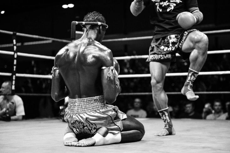 two men sitting on the ground in front of an audience while one man holds his leg up