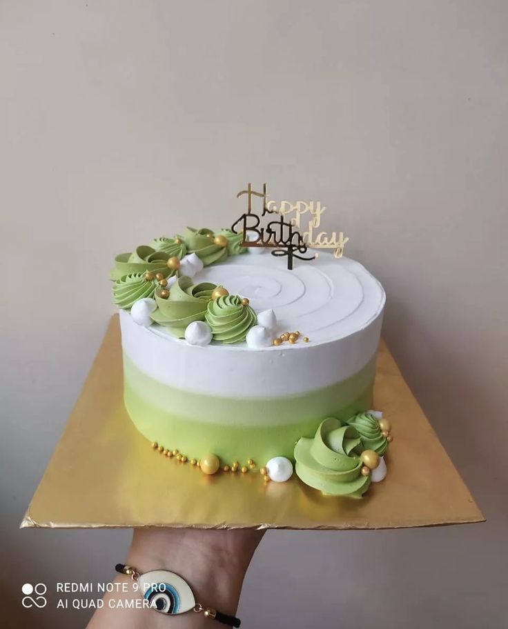 a birthday cake with green and white frosting on top is being held by a person