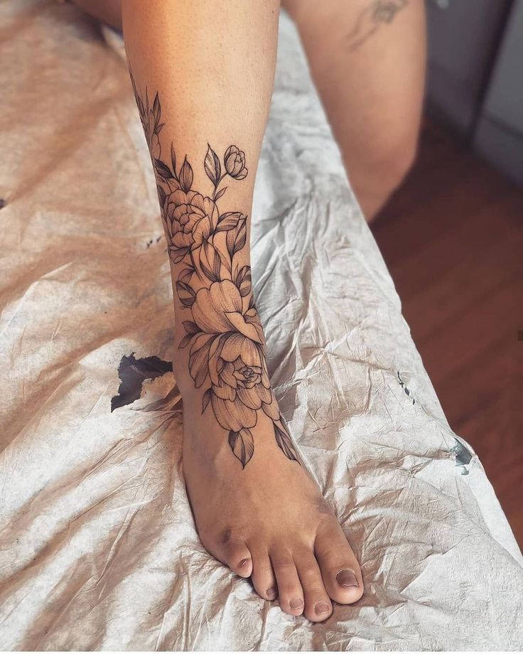 a woman's foot with a flower tattoo on her left leg and the bottom part of her body